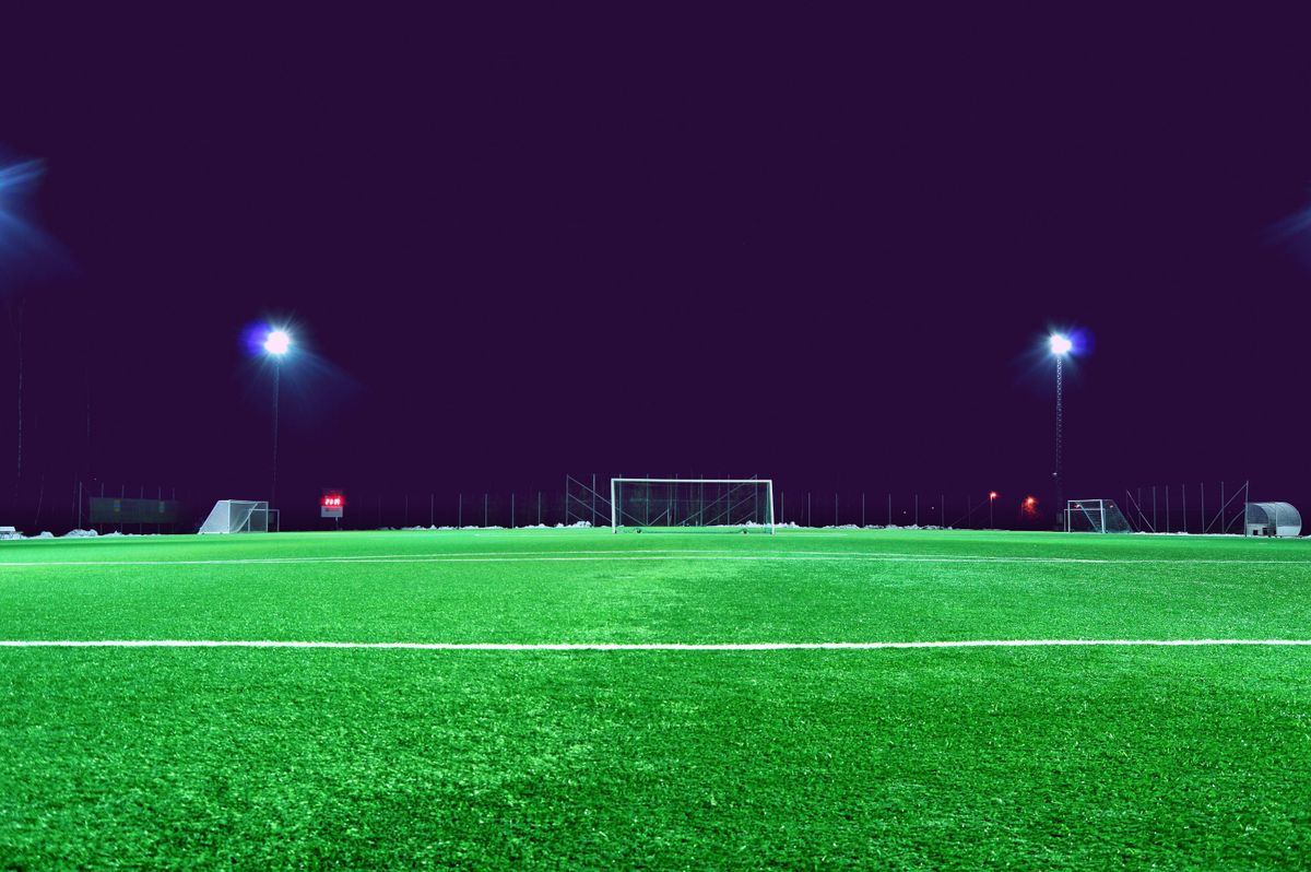 Lapangan sepak bola menyala di malam hari dengan gawang