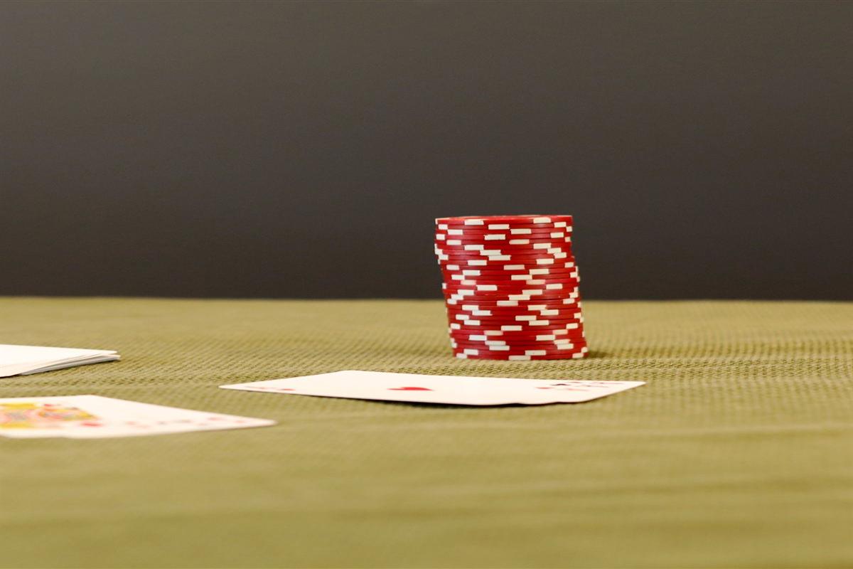 Chip poker merah tersusun di meja hijau